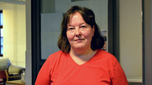 Jaana Vilponen är just nu på praktik i Delaktighetsvardagsrummet, hon skulle gärna fortsätta med någon typ av projektarbete. En kvinna med brunt axellångt hår och röd v-ringad blus tittar rakt in i kameran.