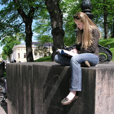 En flicka sitter vid Åbo Domkyrka och studerar.