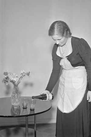 På 1900-talet kunde man bättre. Det mineralhaltiga källvattnet Kirvu hälls bevisligen upp i glas. Dam i förkläde häller upp källvattnet Kirvu i ett glas från en flaska.