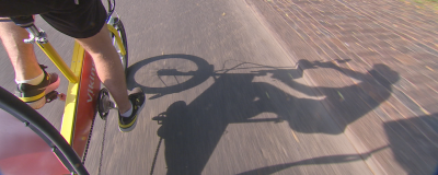 Pedalarna och skuggan av en cykeltaxi syns mot asfalten.