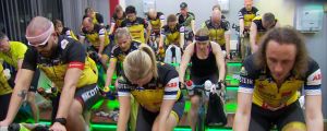 Ett team tränar på spinningcyklar inomhus. En grupp cyklister tränar på spinningcyklar inomhus.