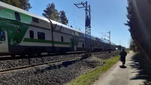 Tågresor skulle vara lönsammare om fler åkte tåg. En tåg kör förbi en cyklist på en grusväg.