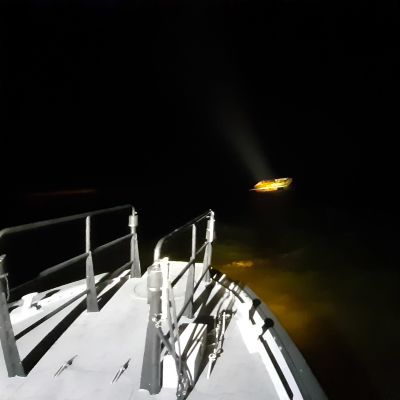En båt vars däck syns och längre bort syns en sjunkande bastuflotte i havet.