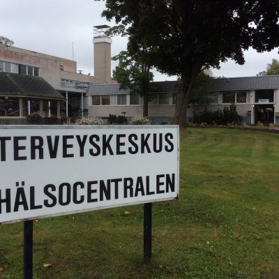 Hangö hvc, sliten 1970-talsbyggnad, i förgrunden en skylt med texten Terveyskeskus-Hälsocentralen.