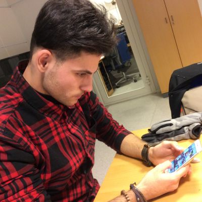 En ung man tittar på sin telefonskärm.