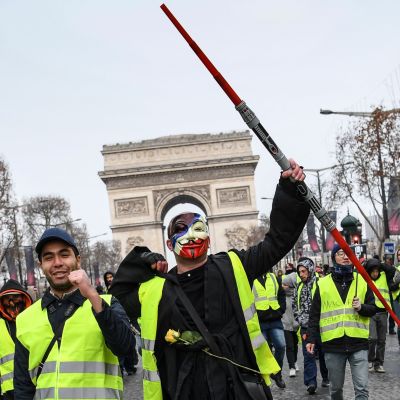 Demonstranter i gula västar går längs framför triumbågen i Paris