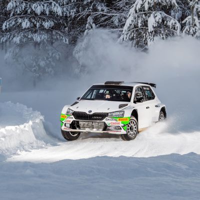 En vit rallybil kör i snö.