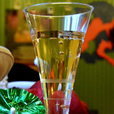 ett glas med bubblig dryck och en massa huvudbonader på varandra i olika färger och ett litet glassparaply i grönt