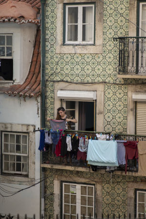 Efterfrågan på fastigheter stöper om de traditionella kvarteren i centrala Lissabon. En kvinna hänger upp tvätt på en balkong till ett gammalt hus i Lissabon.