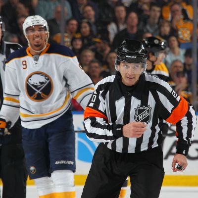 Evander Kane naureskelee taustalla, tuomari Tim Peel luistelee kohti kameraa.