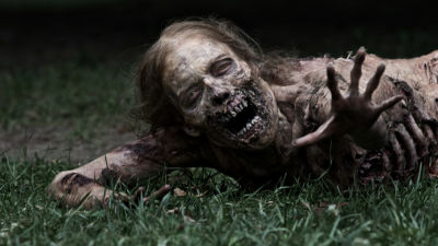 En zombie på marken sträcker ut handen i tv-serien The Walking Dead.