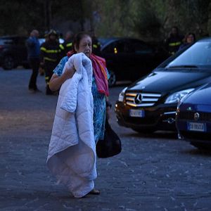 En kvinna som har tillbringat natten ute går längs en gata med ett täcke i famnen