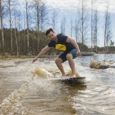 Mies liirtolaudan päällä rantavedessä.