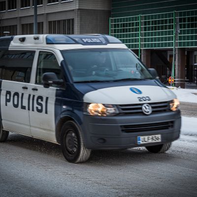 Poliisiauto kulkee lumisella kadulla.