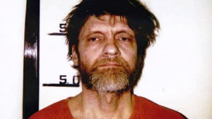 Theodore Unabomber Kaczynski som han såg ut när han hade blivit satt i fängelse. skäggig ovårdag man i röd fångdräkt står mot vit vägg och ser trött ut
