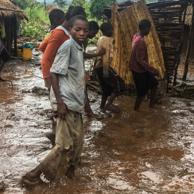 Invånare i en by går längs en översvämmad väg i Moçambique.