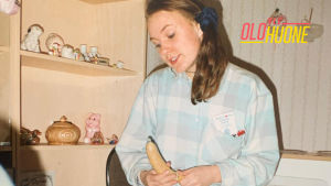 Teini-ikäinen Mira Luoti istuu huoneessaan. Kädessään hänellä on banaani, jonka päälle on puettu kodomi.