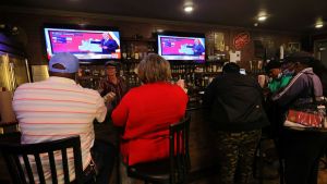 Senatsvalet i Georgia har väckt mycket intresse eftersom det avgör maktbalansen i senaten. Människor sitter på barstolar vid en bardisk i Atlanta, USA. De tittar upp på en TV där man följer med rösträkning i senatsvalet i Georgia.