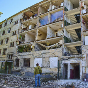 Mies katsoo tuhoutunutta asuinrakennusta Harkovassa.