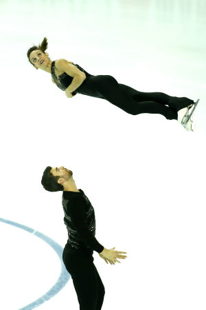Meagan Duhamel/Eric Radford gör ett lyckat trippeltwistlyft i korta programmet i Grand Prix-finalen i Marseille. Paråkaren Eric Radford tittar upp mot sin partner Meagan Duhamel som roterar högt över hans huvud.