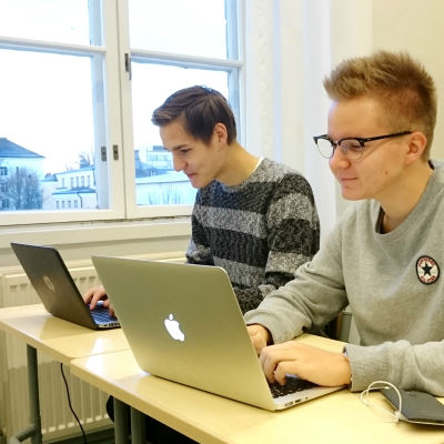 Två skolelever jobbar vid sina datorer under en lektion.
