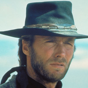 Lähikuvassa parrakas Clint Eastwood päässään musta nahkainen lierihattu katsoo sirmät sirrillään jonnekin kameran ohi, taustalla pilvistä taivasta, kuva elokuvasta Ruoska eli High Plains Drifter.