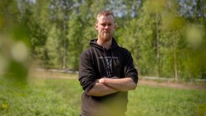 Eero Kortesniemi har träffat en kvinna men han vågar inte säga om de sällskapar ännu. Porträtt av en man som står i sommargrönskan på en grön åker.