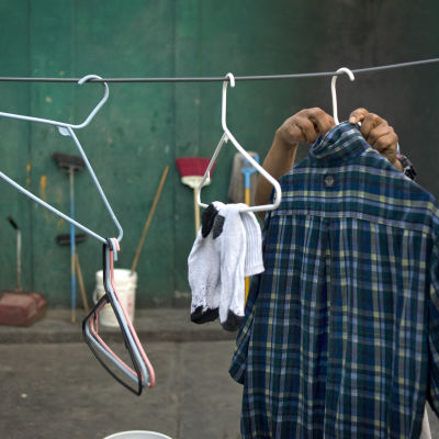 En hemlös man hänger upp sina kläder på tork en bakgård.