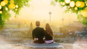 Nainen ja mies istuvan toisiaan vasten kalliolla katsellen surrealistista maisemaa.