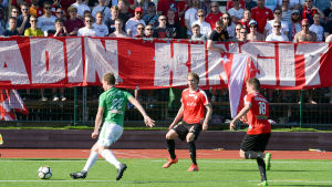 HIFK har två poäng upp till ettan EIF i serietabellen. En bild på en fotbollsspelare i grönvitt (EIF) som sparkar på en boll. Bredvid honom finns spelare i rött och svart. Bakom fotbollsspelarna finns en banderoll där det står stadin kingit - de stöder laget i rött och vitt (HIFK)