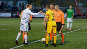 EIF:s lagakpten Zacharias Ekström hälsar på kollegan Lassi Nurmos i AC Oulu. Lagkaptenerna Zacharias Ekström (EIF) och Lassi Nurmos (AC Oulu) hälsar på varandra före matchen. På bilden ses också domaren Joni Hyytiä.
