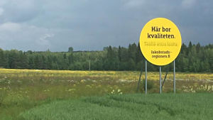 I Jakobstadsregionen bor kvaliteten sedan 2011. en rund och gul skylt på en äng. på skylten står det här bor kvaliteten.