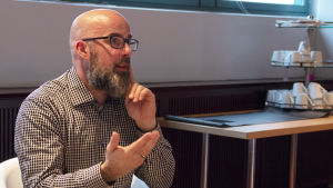 Oskari Salomaa toivoo tekstityksiä jääkiekko-otteluihin. Oskari Salomaa viittoo. Hän on yksi Yle-raadin jäsenistä.