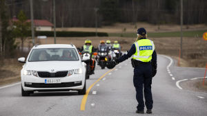 Poliisi pysäyttää auton ja moottoripyöriä Pukkilan karanteeni rajalla.