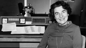 Radiokuuluttaja Kaisu Puuska-Joki istuu studion tuolilla ja hymyilee kameralle vuonna 1960.
