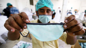 En fabrik i Pakistan tillverkar dessa andningsskydd. Pakistan är ett av de ledande länderna i Asien när det kommer till tillverkning av skyddsutrustning. Man håller upp ett ansiktsskydd