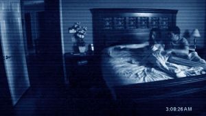Paranormal Activity är en av de filmer som framkallar mardrömmar. En man och en kvinna sitter i sängen mitt på natten och ser mot en öppen dörr.