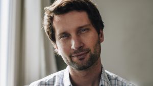 Michal Kosinski uppfann en sökmaskin för människor som mot hans vilja blev en väsentlig del av Donald Trumps valkampanj. Porträtt av Michal Kosinski med rågblont hår, kort skägg och en vit skjorta med gråblåa rutor.