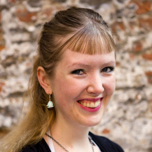 Fotografen Milla Vahtila önskar kunna få bo kvar i regionen. Arkivbild. Leende kvinna mot stenvägg.