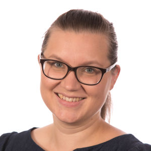 Rebecka Stråhlman säger att temasångerna är viktiga för henne personligen. Porträttbild av Rebecka Stråhlman, i svart tröja och det mörkbruna håret i hästsvans ler hon mot fotografen.