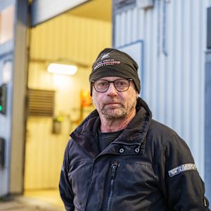 En man står utanför en bilverkstad.