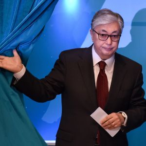 Kassym-Jomart Tokayev stiger fram bakom ett blått draperi.