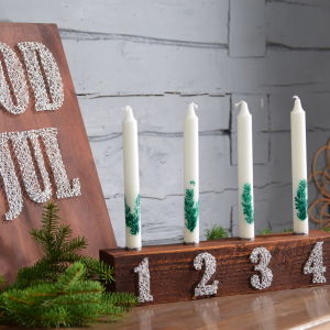 En adventsljusstake med siffror och en tavla med texten god jull 