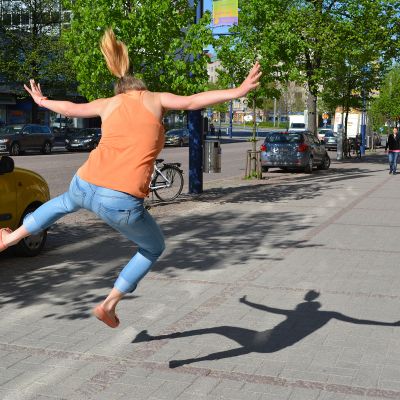 Nainen hyppää ilmaan kadulla. 