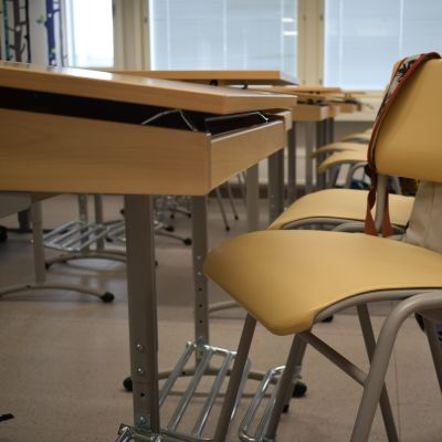 Koulureppu ja tyhjä pulpetti luokkahuoneessa.
