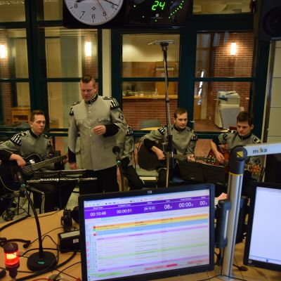 Viisi sotilasasuista soittajaa radion lähetysstudiosa.