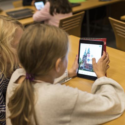 Lapsia käyttämässä tablettitietokonetta.