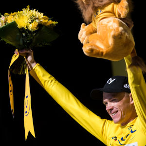Chris Froome i den gula ledartröjan höjer upp blomkrans och mjukisdjur.