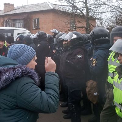 En kvinna gestikulerar och skriker åt en grupp kravallpoliser