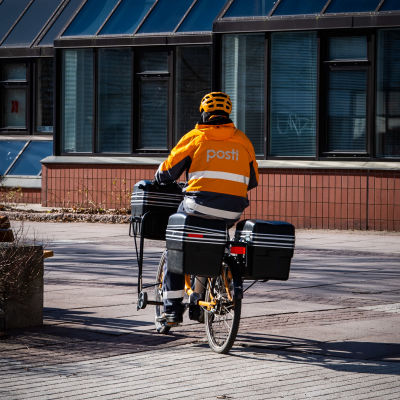 Postinjakelija jakaa postia polkupyörällä.